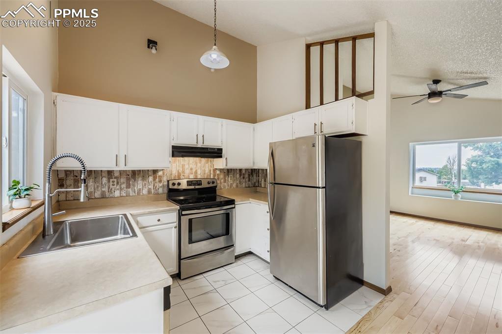 Image 6 of 45: Kitchen featuring stainless steel appliances, white cabinetry, decorative b