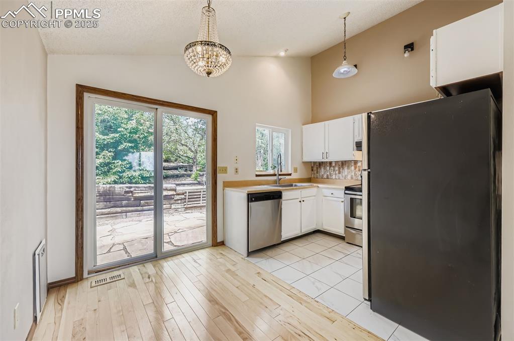 Image 7 of 45: Kitchen with appliances with stainless steel finishes, white cabinetry, lig