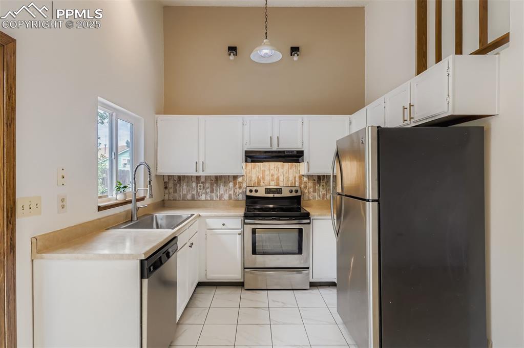 Image 8 of 45: Kitchen featuring stainless steel appliances, white cabinetry, light counte