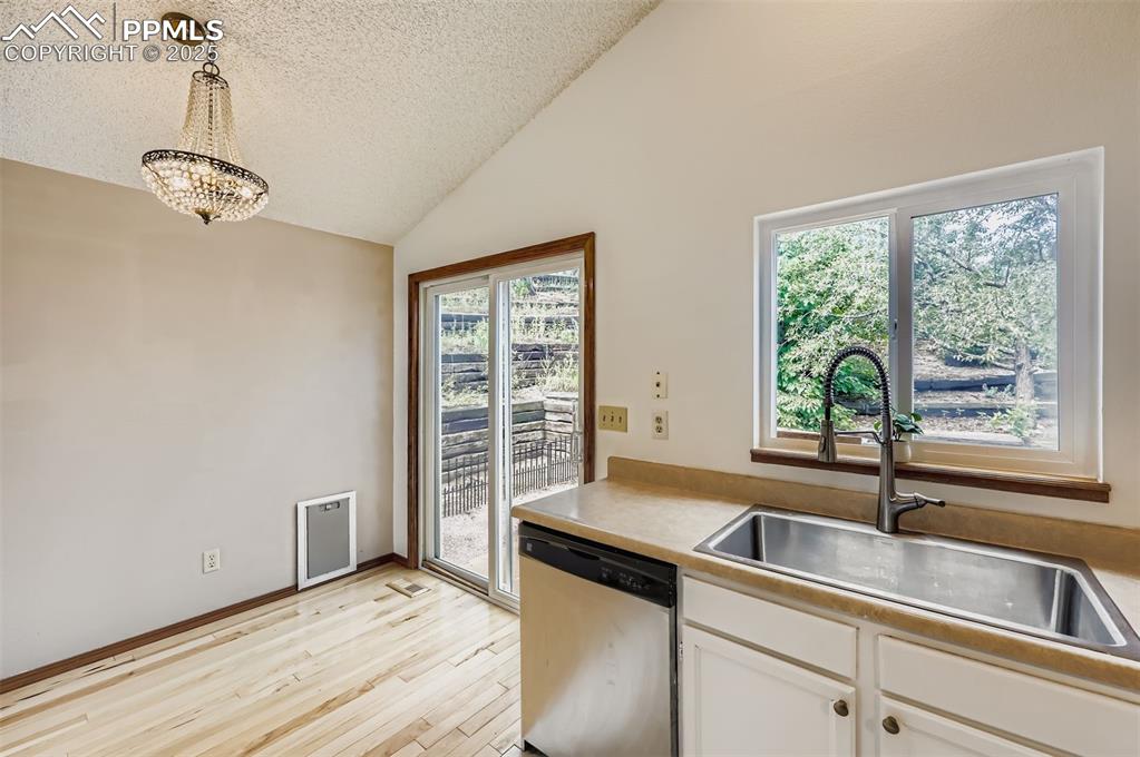 Image 9 of 45: Kitchen featuring dishwasher, hanging light fixtures, plenty of natural lig