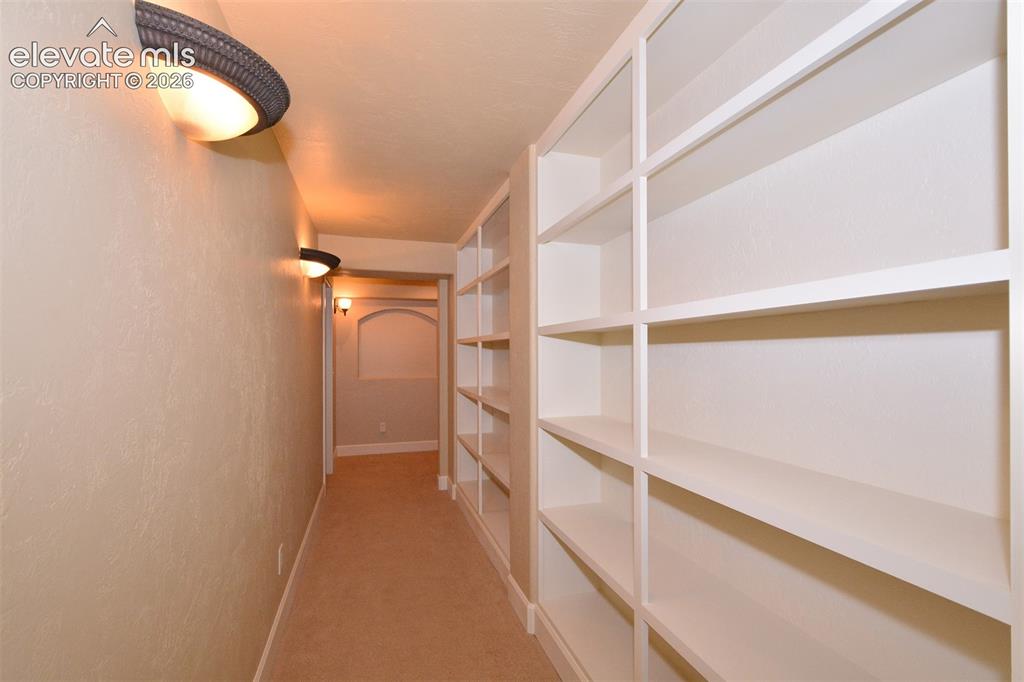 Image 25 of 31: Hallway with built-in bookshelves in basement