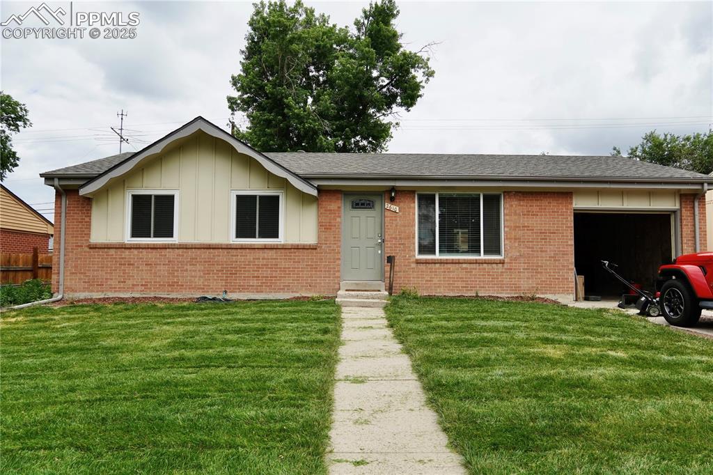 Caption: Ranch-style house with board and batten siding, a front lawn, an attached garage, and roof with shin