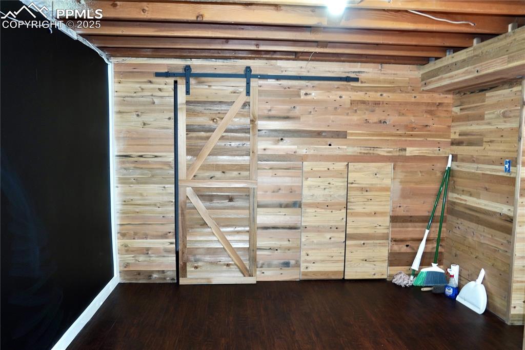 Image 10 of 23: Spare room featuring dark wood-style flooring and wood walls
