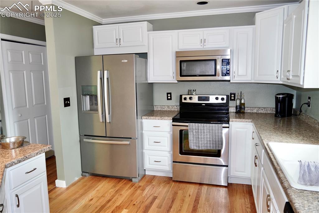 Image 14 of 23: Kitchen featuring appliances with stainless steel finishes, white cabinets,