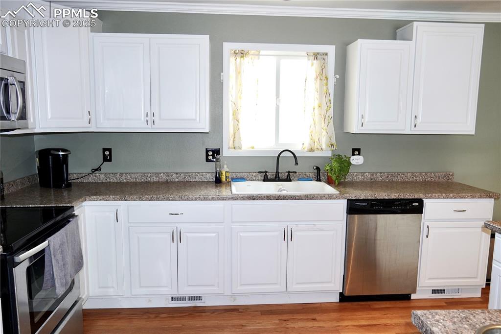 Image 15 of 23: Kitchen with white cabinetry, stainless steel appliances, light wood-type f