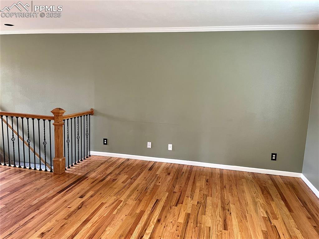 Image 18 of 23: Empty room with ornamental molding and wood finished floors