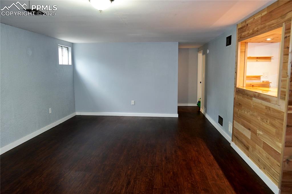 Image 8 of 23: Empty room featuring dark wood-style floors and baseboards
