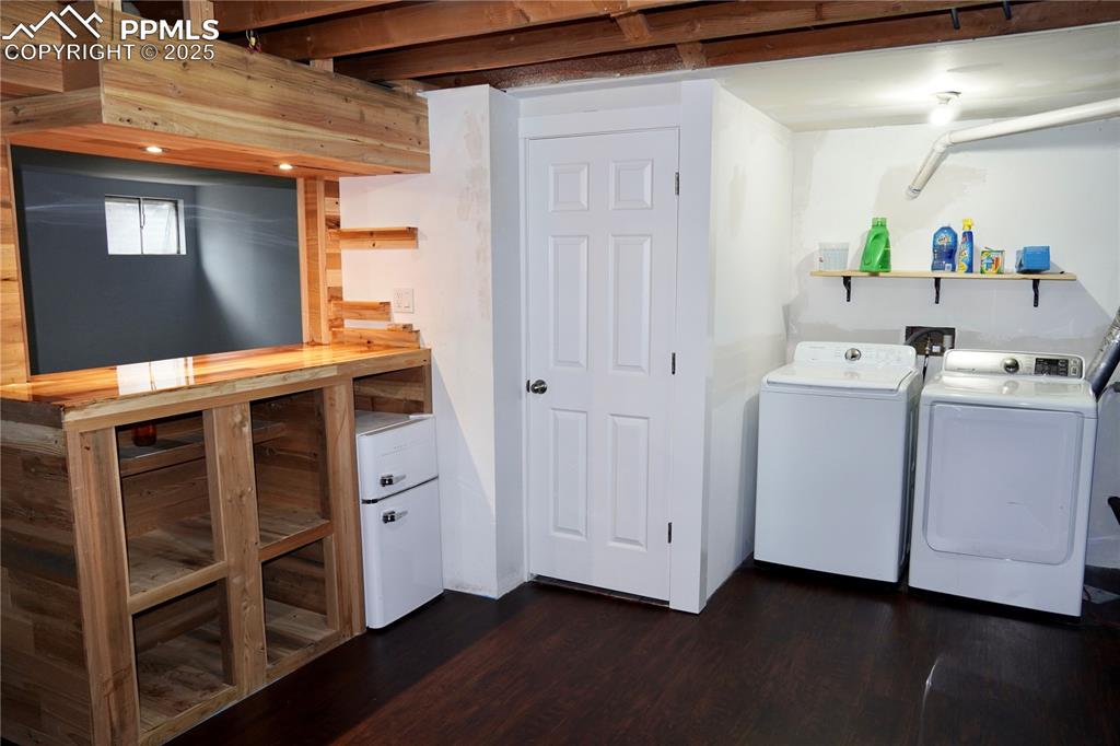 Image 9 of 23: Laundry room featuring dark wood-style floors and washer and clothes dryer