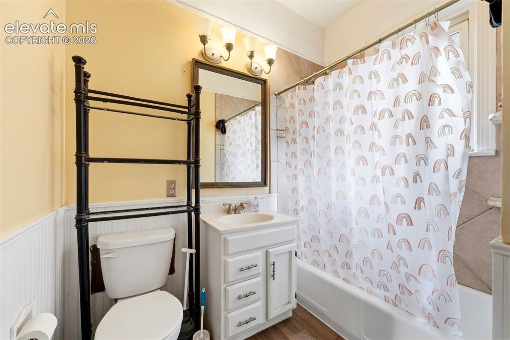 Image 12 of 35: White vanity with integrated sink, wood-finish flooring, a white bathtub, a
