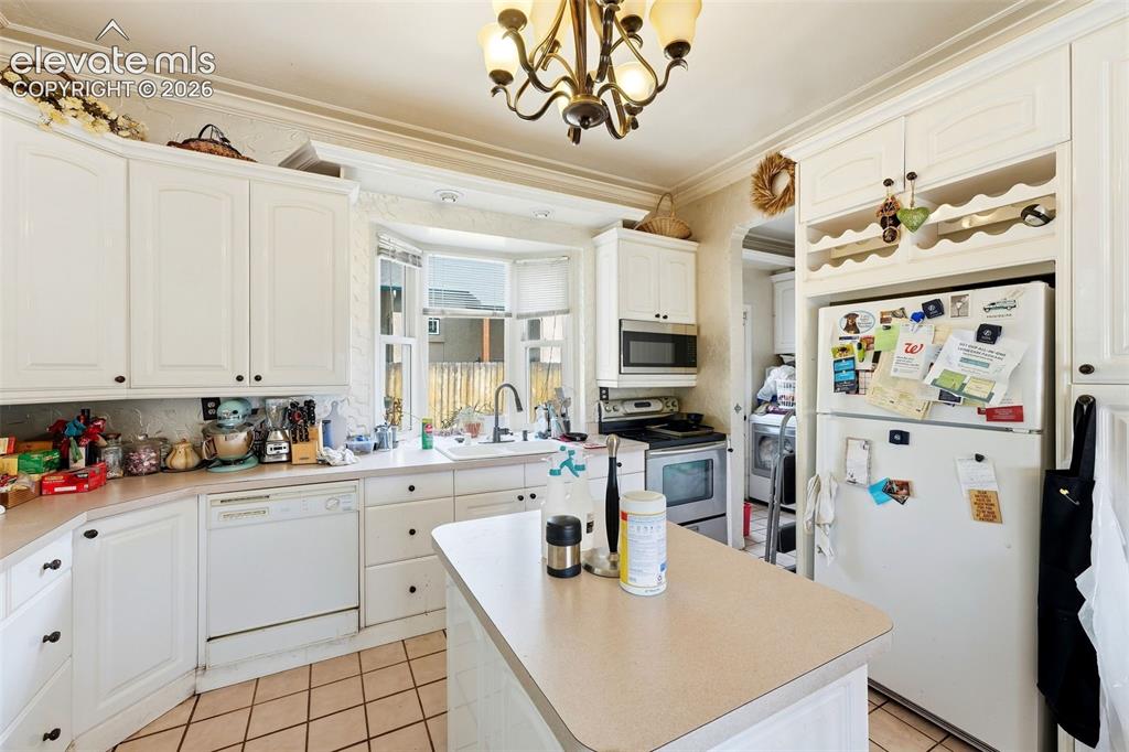 Image 15 of 35: Kitchen featuring white cabinetry, a bay window, a central island, tile flo