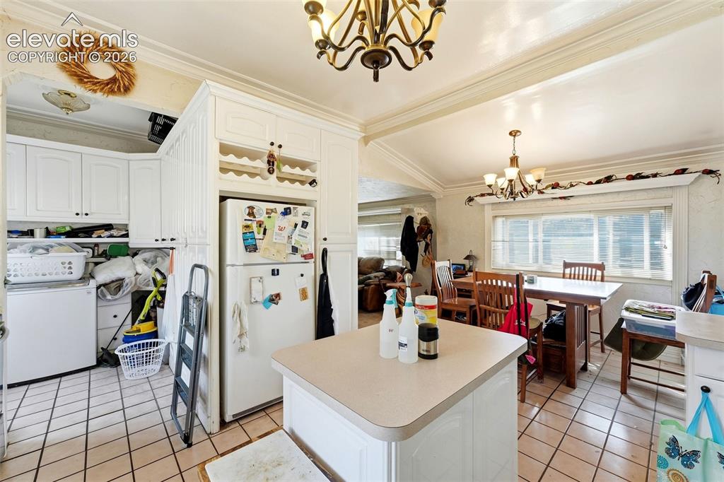 Image 16 of 35: White cabinetry with built-in wine rack, centered kitchen island, and tile 