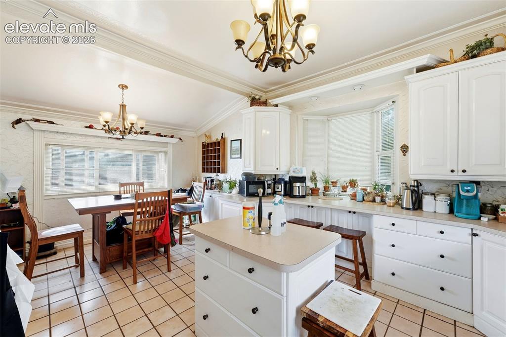 Image 17 of 35: White cabinetry with black hardware, bay window, tile flooring, and a centr