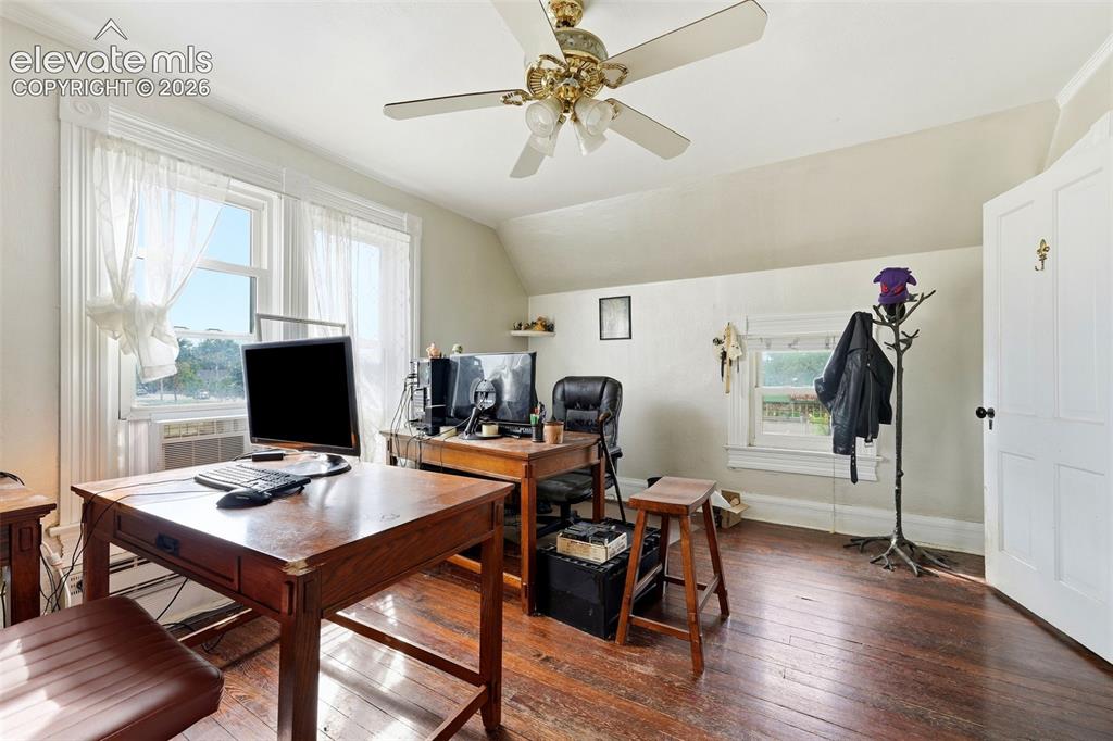 Image 20 of 35: Hardwood flooring, multiple windows, ceiling fan, white paneled door, slope