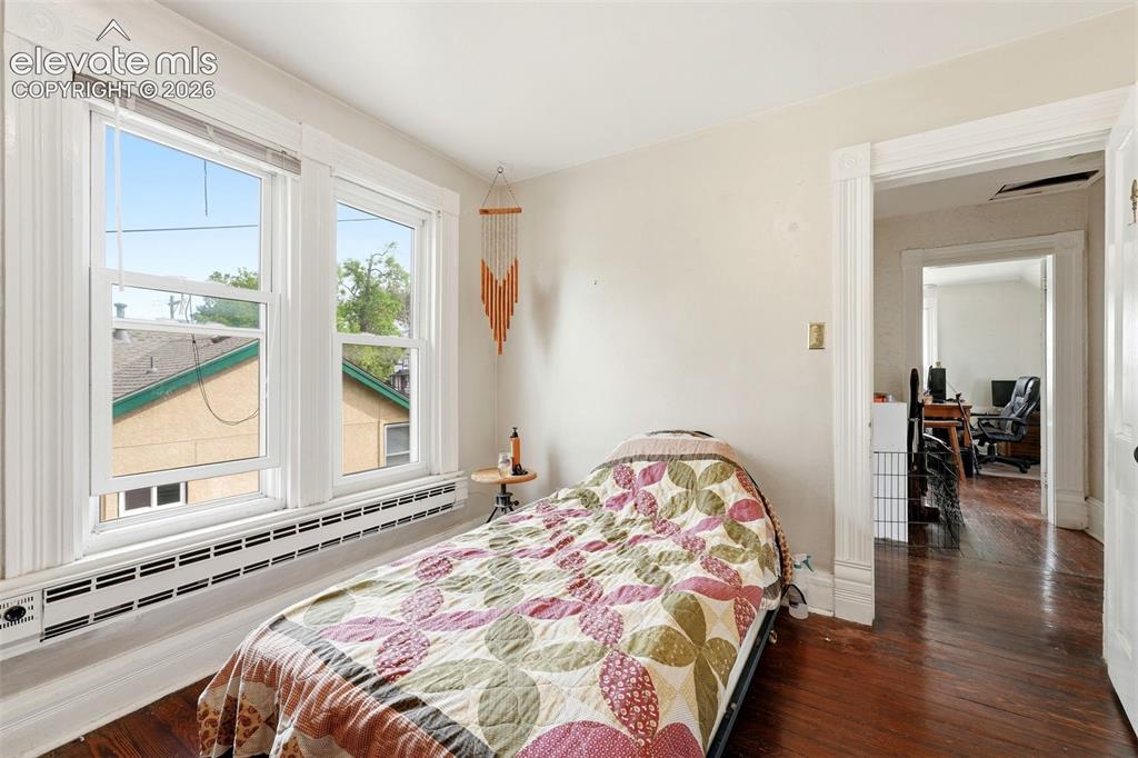Image 23 of 35: Hardwood flooring throughout, two large windows with white trim, and a buil