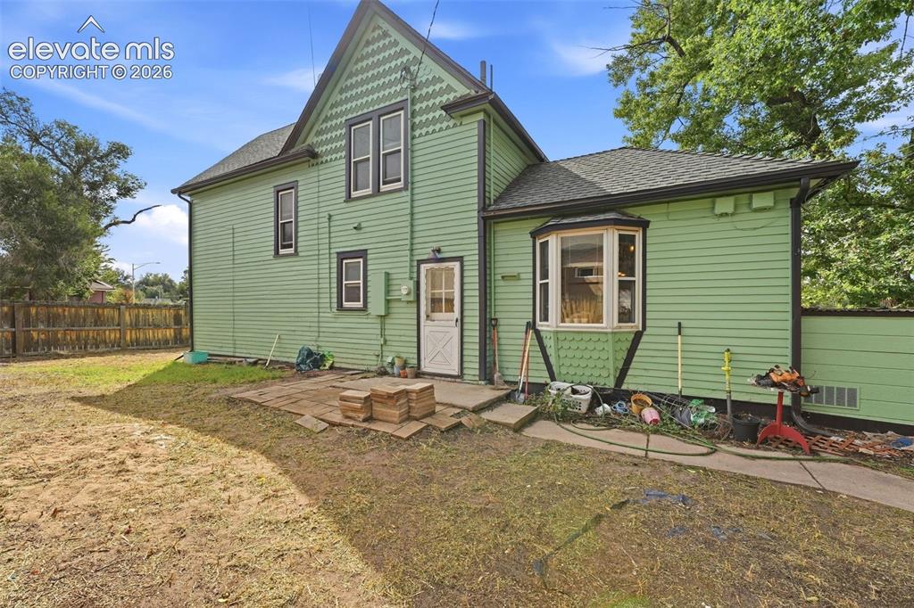 Image 30 of 35: Rear exterior showcasing light green siding, black trim, a bay window, and 