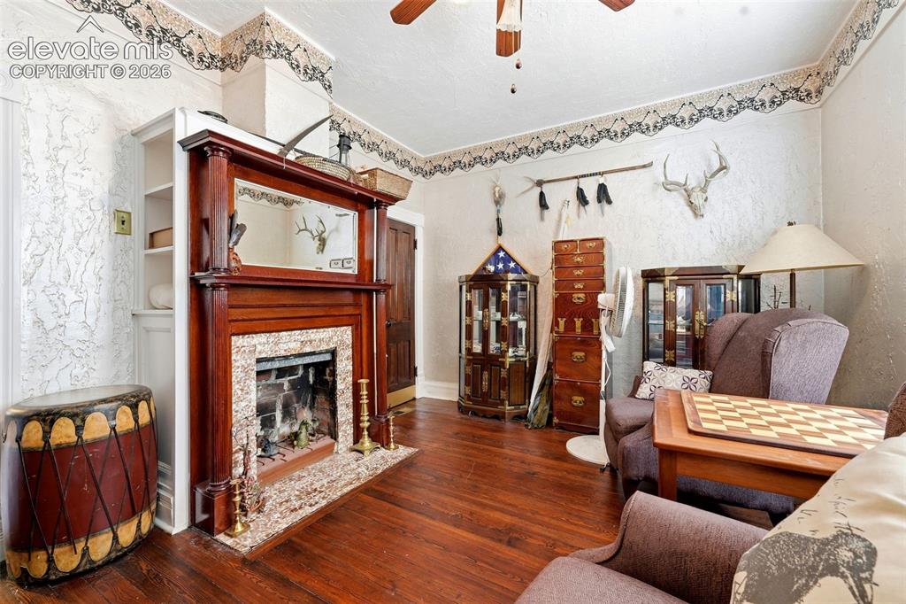 Image 5 of 35: Wood-finish flooring, built-in shelving, wood-mantled fireplace with a ston