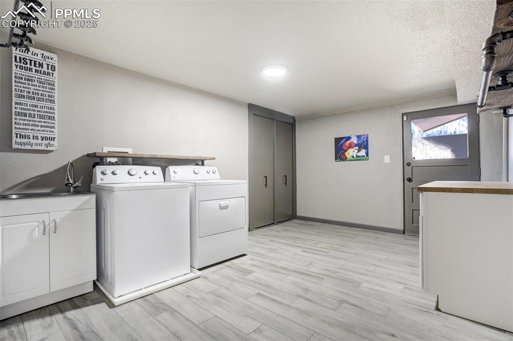 Image 39 of 50: Lower level laundry with access to the outside. Sink and cabinets