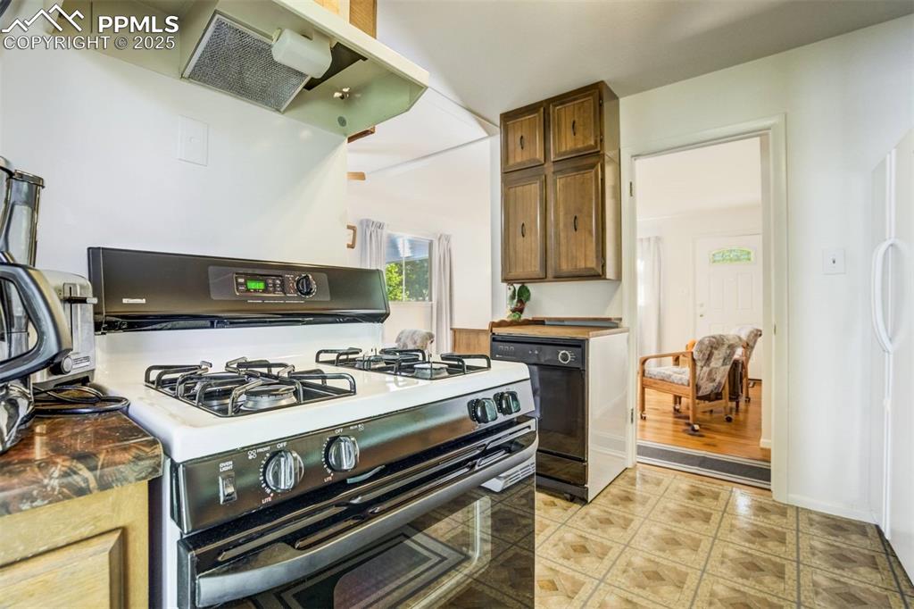 Image 14 of 47: Kitchen featuring range with gas stovetop, range hood, brown cabinets, dark