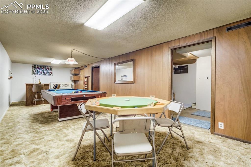 Image 30 of 47: Game room featuring wooden walls, light colored carpet, pool table, and a t