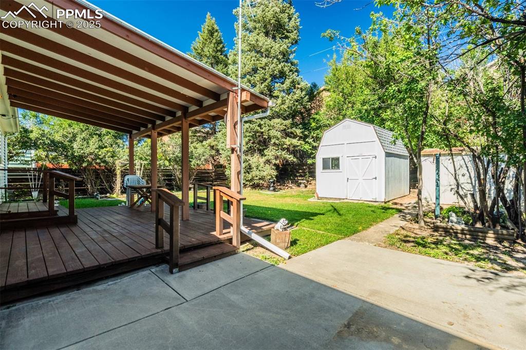 Image 38 of 47: Fenced backyard featuring a wooden deck and a storage shed