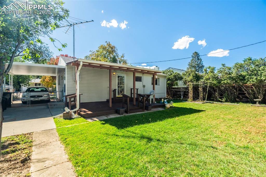 Image 41 of 47: Rear view of house featuring an attached carport, a wooden deck, and concre