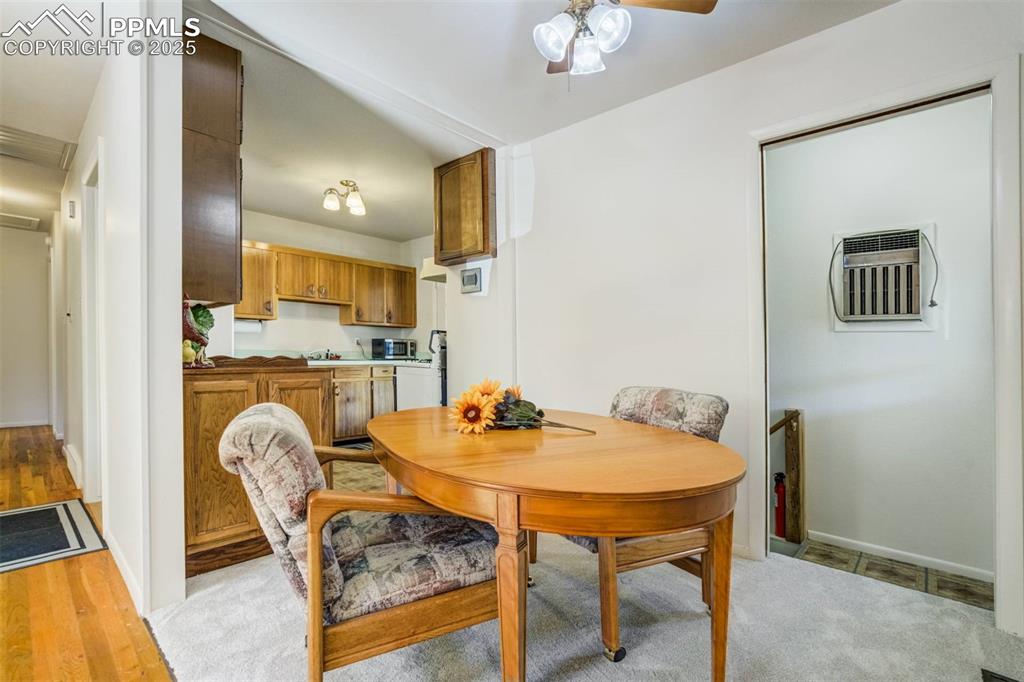 Image 8 of 47: Dining space with an AC wall unit, ceiling fan, and light wood-style floori