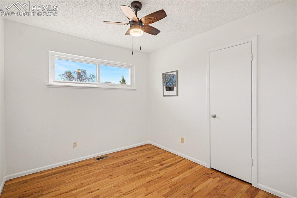 Image 10 of 21: Secondary bedroom with real wood flooring & new ceiling fan