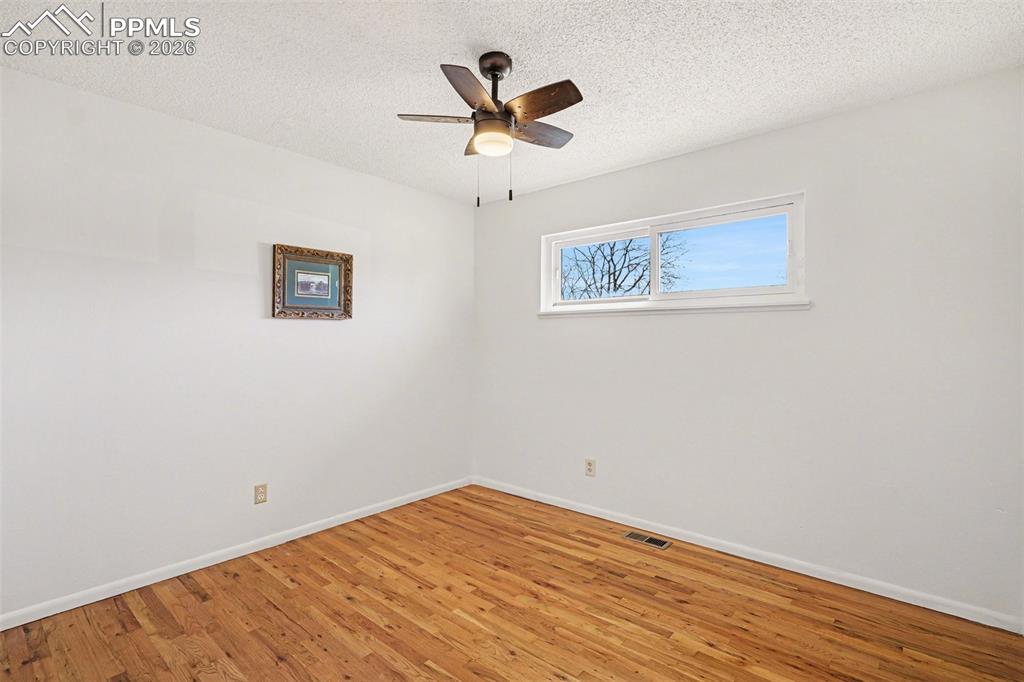 Image 11 of 21: Secondary bedroom with real wood flooring & new ceiling fan