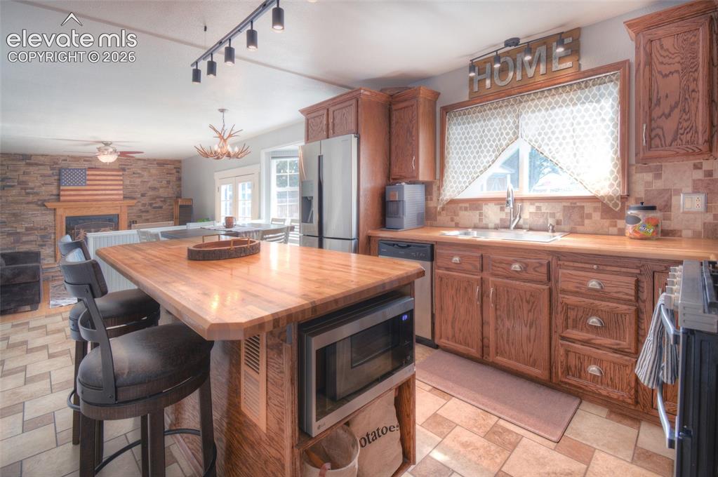 Image 10 of 26: Large kitchen island with warm cabinetry, large window with view to the bac