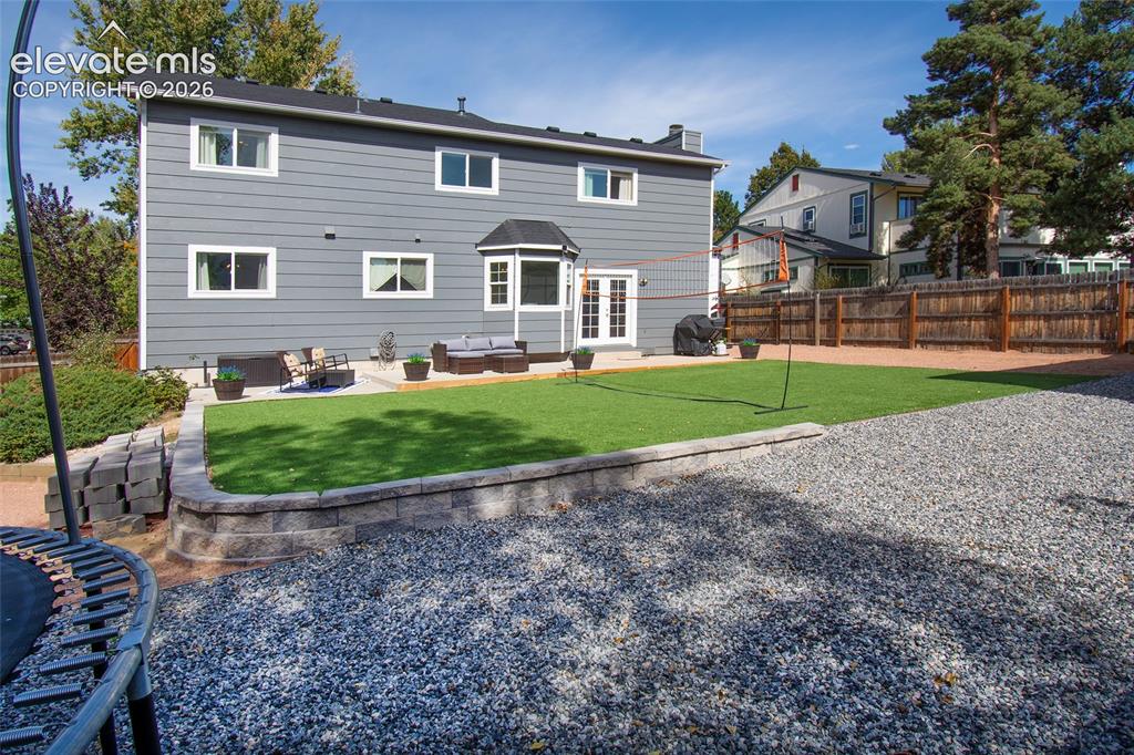 Image 7 of 26: Fully fenced, landscaped backyard with year round green grass, decorative r