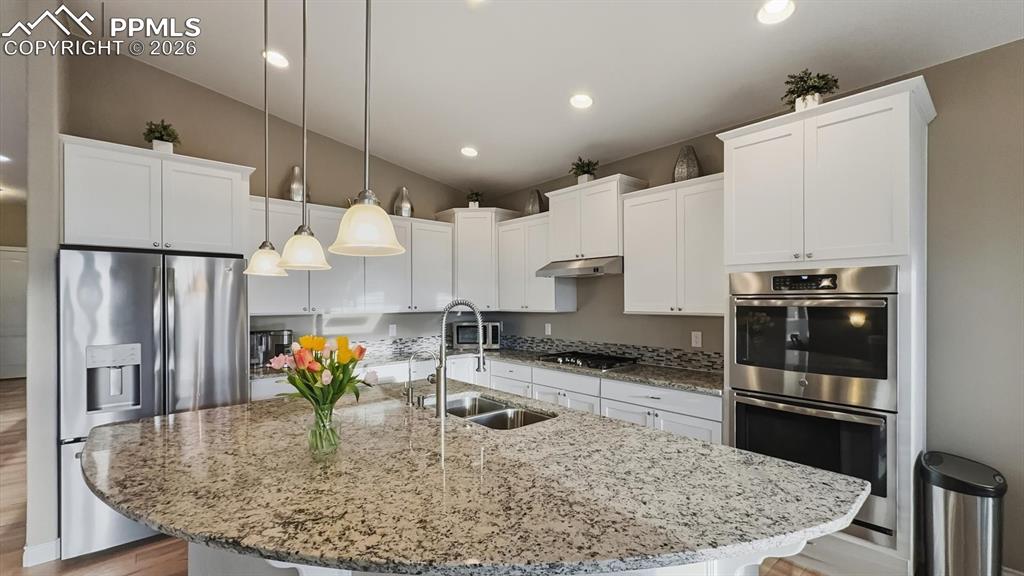 Image 19 of 50: Gorgeous curved granite island in Kitchen with breakfast bar and pendant li