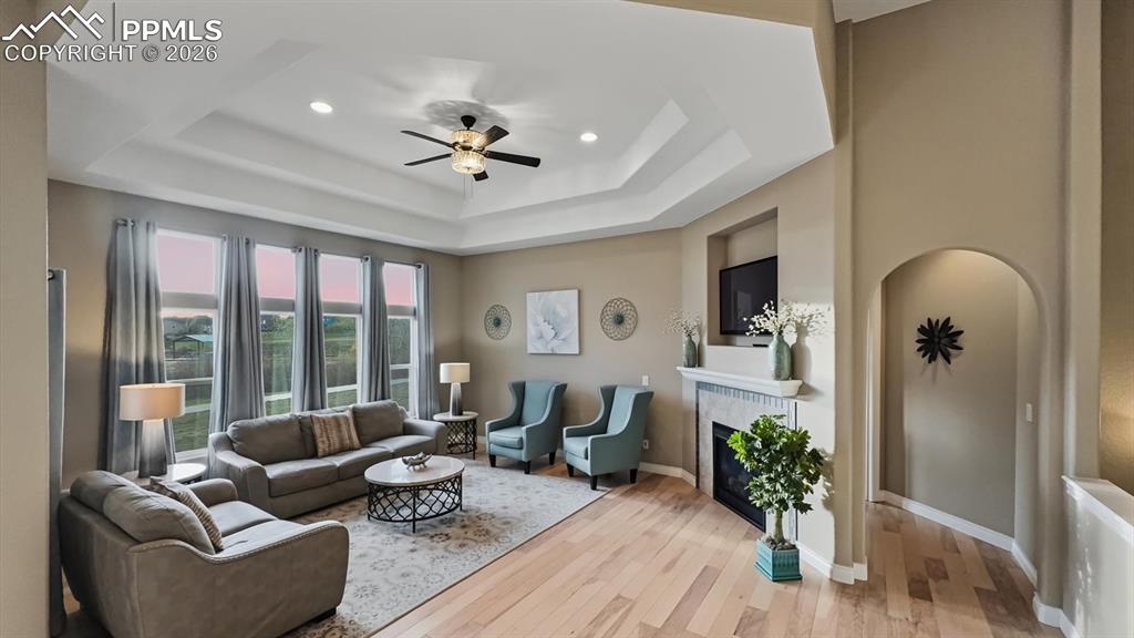 Image 4 of 50: Elegant Living Room with tray ceiling, lighted ceiling fan, and wall of win