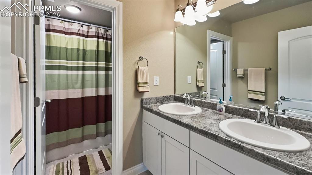 Image 43 of 50: Basement Full Bathroom with dual sink vanity, mirror, and tiled tub/shower.