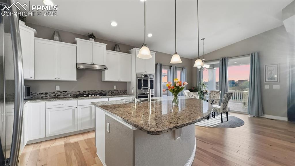 Image 5 of 50: Island Kitchen with granite countertops, breakfast bar, pendant lights, and