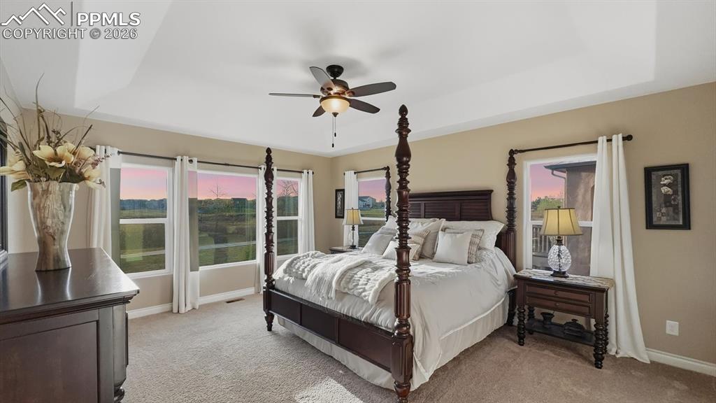 Image 7 of 50: Primary Bedroom with neutral carpet, a lighted ceiling fan, wall of windows