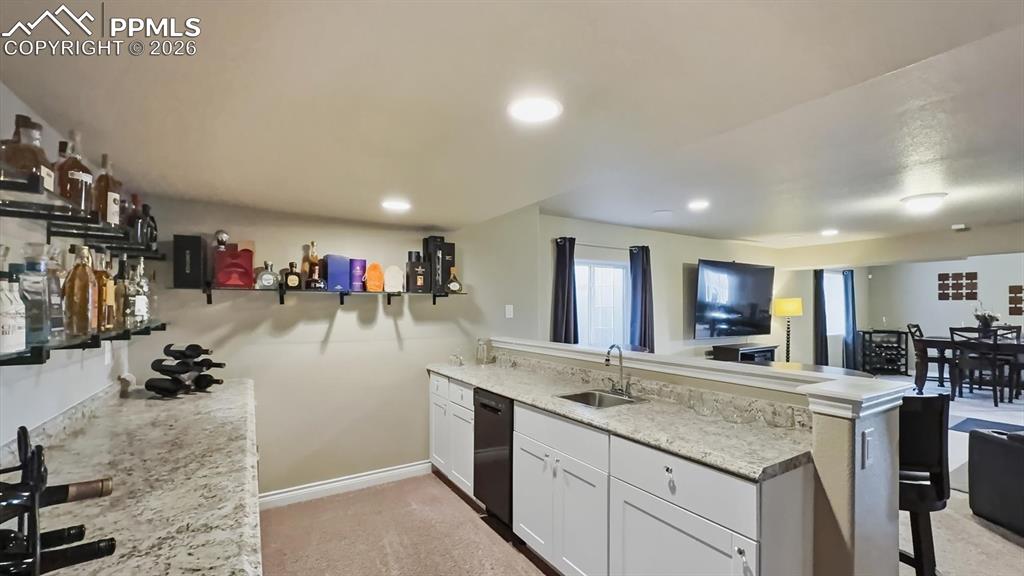 Image 9 of 50: Basement wet bar with granite countertops, dishwasher, wine fridge, and bev