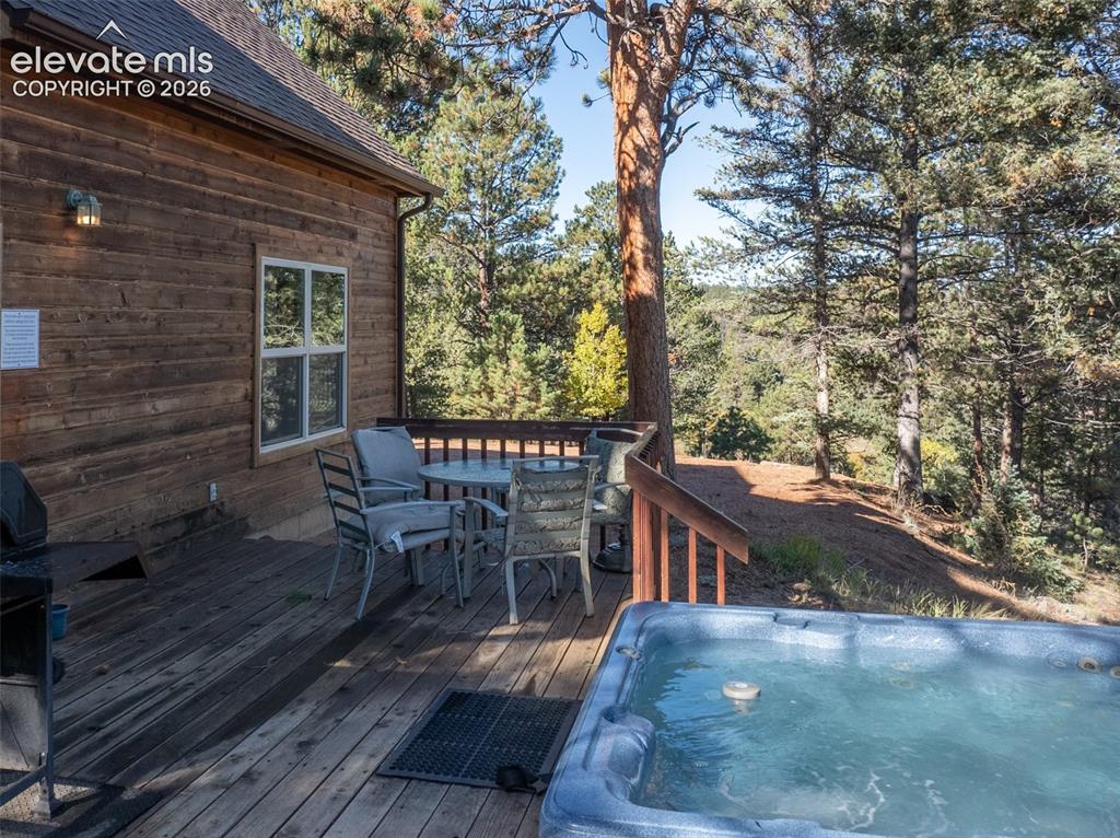 Image 16 of 50: Expansive wooden deck with a built-in hot tub, offering abundant natural li