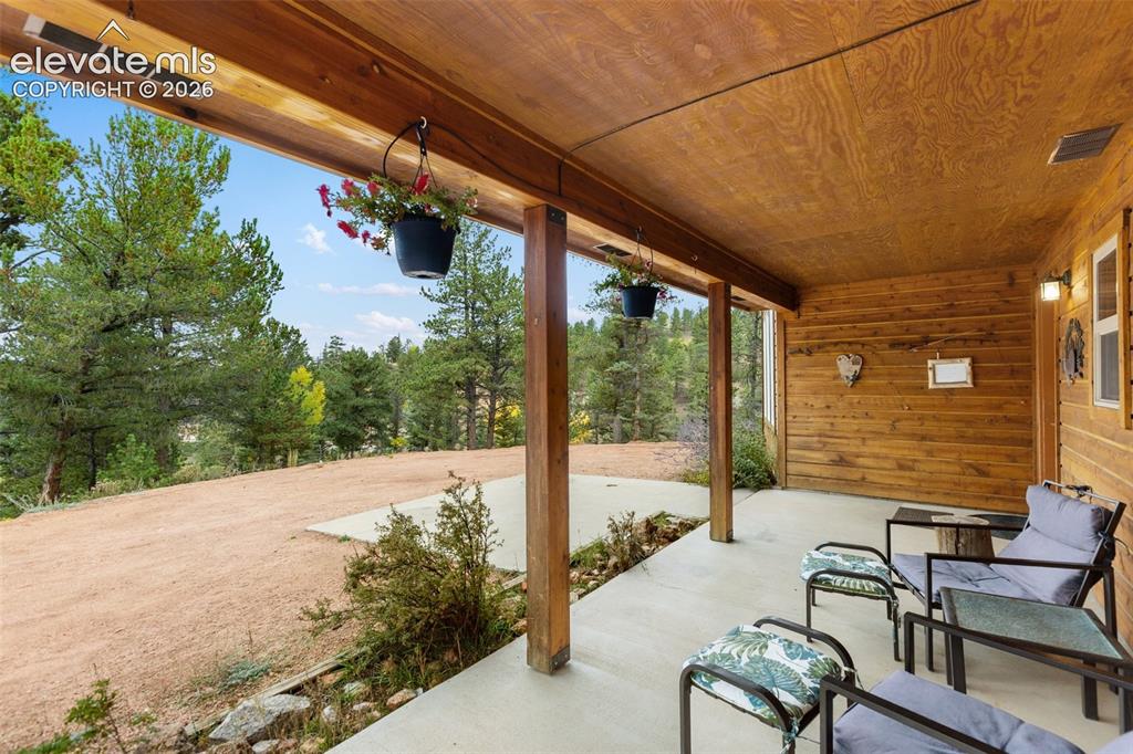 Image 2 of 50: Covered outdoor patio featuring a wood-paneled ceiling, wood-finish columns