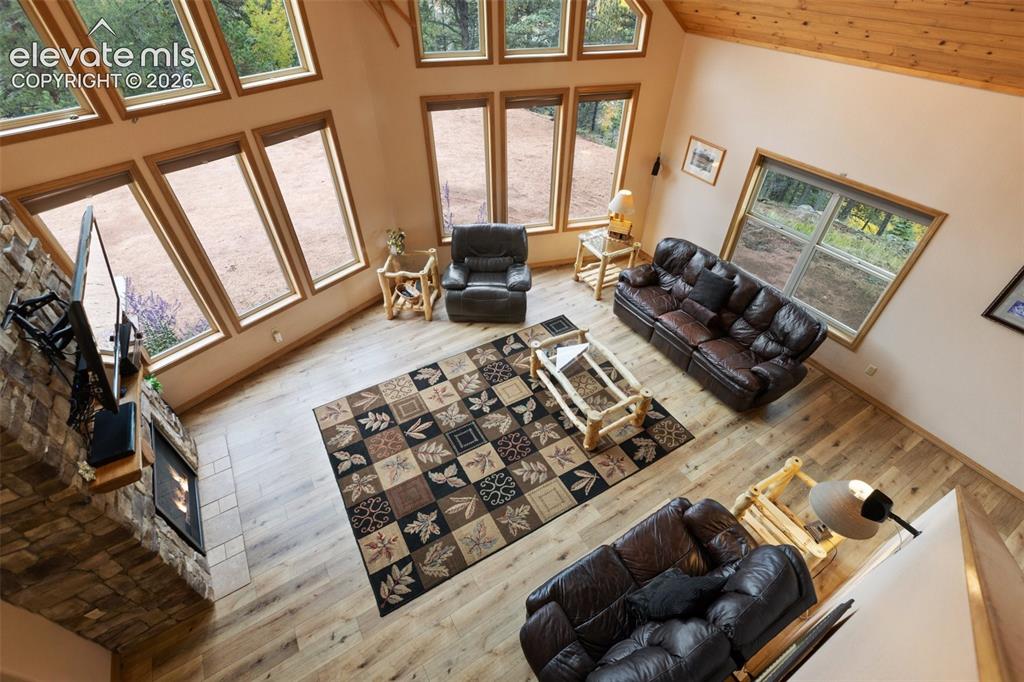 Image 20 of 50: Vaulted wood-paneled ceiling, stone-clad fireplace, wood-finish flooring, a