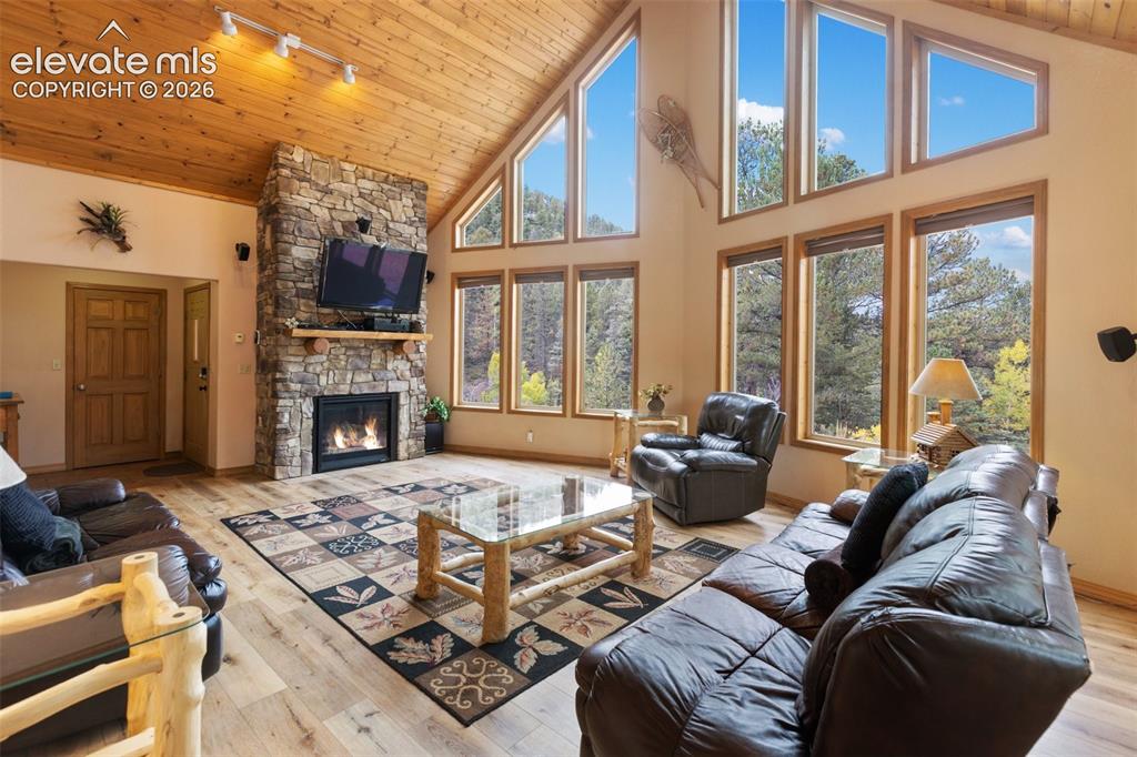 Image 21 of 50: Vaulted wood-paneled ceilings, stone-clad fireplace with mantel, expansive 