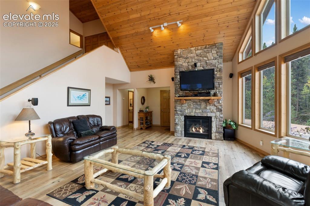 Image 22 of 50: Vaulted wood-paneled ceiling, stone fireplace with mantel, hardwood floorin