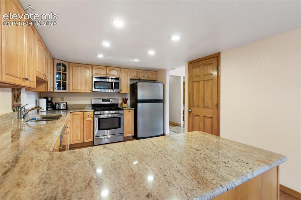 Image 32 of 50: Kitchen featuring wood cabinetry, light-toned countertops, stainless steel