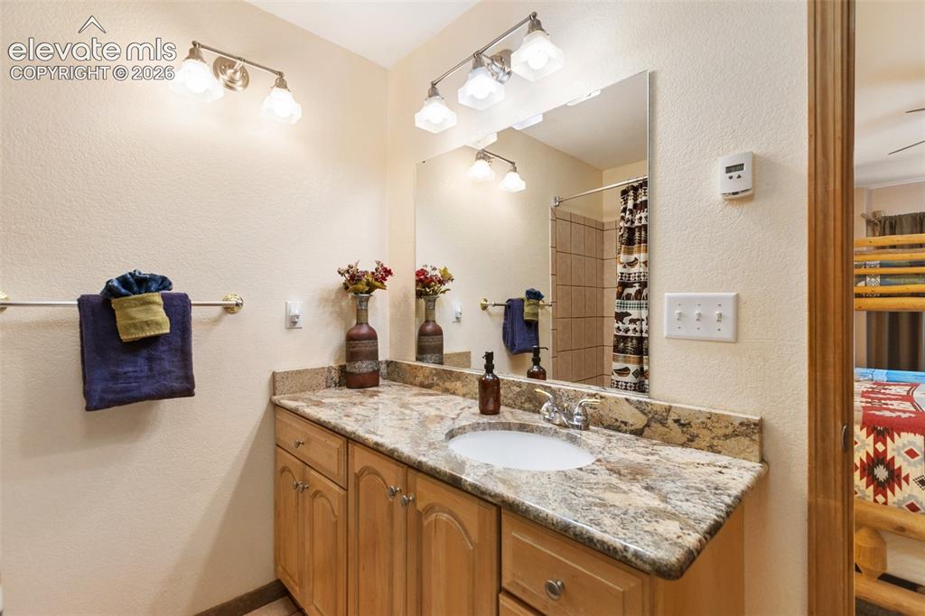 Image 35 of 50: Vanity with light wood-finish cabinetry, stone countertop, undermount sink,