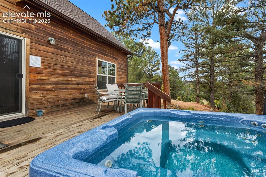 Image 48 of 50: Private deck with a built-in hot tub, offering an outdoor dining area, wood