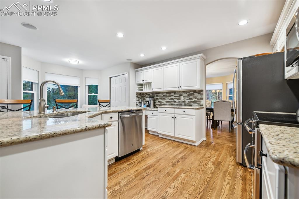 Image 10 of 47: Kitchen with stainless steel appliances, light wood-style floors, white cab