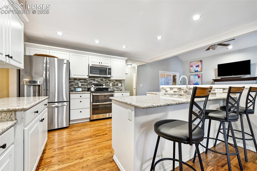 Image 11 of 47: Kitchen with stainless steel appliances, tasteful backsplash, light wood-st