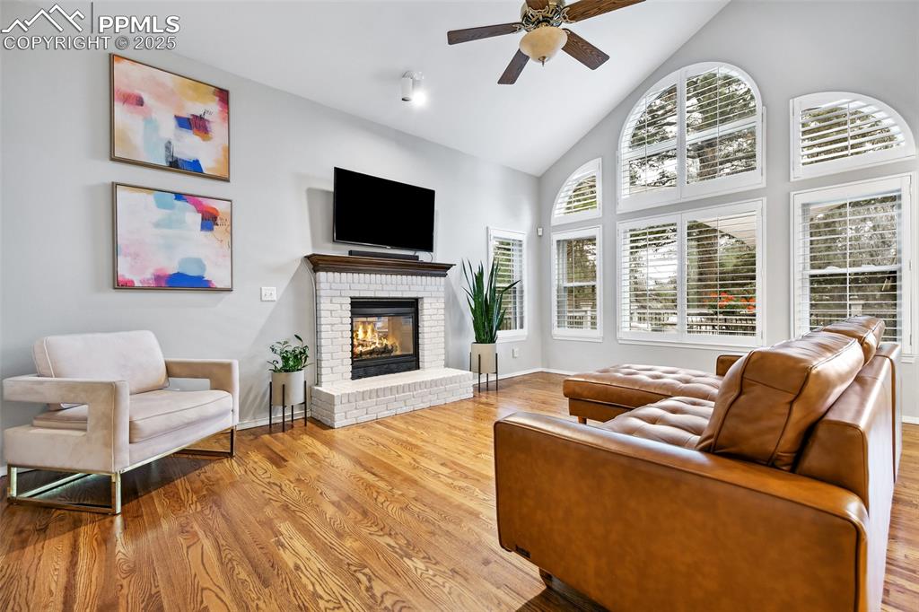 Image 16 of 47: Living room featuring a ceiling fan, wood finished floors, high vaulted cei