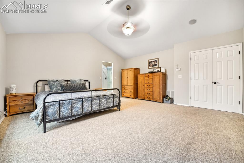 Image 21 of 47: Bedroom with lofted ceiling, light carpet, a closet, and a ceiling fan