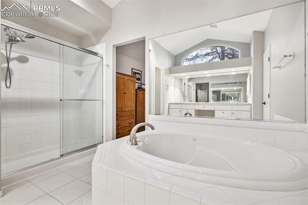 Image 23 of 47: Bathroom featuring lofted ceiling, a shower stall, a garden tub, vanity, an