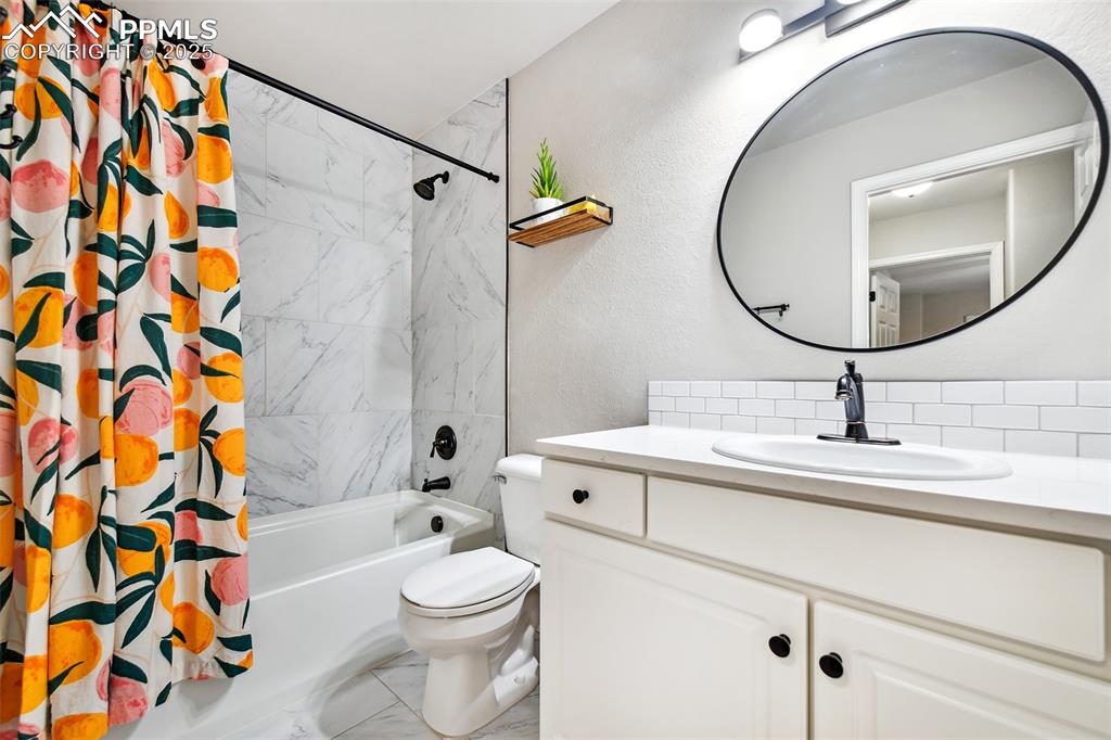 Image 28 of 47: Bathroom with marble finish floors, vanity, shower / bath combination with 